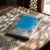 Libro 10 - El orden de las prácticas devocionales regulares (awrad) de Imam Al-Gazzali, sobre una mesa de madera con la sombra de una celosía