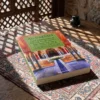 Libro 2 - Los principios de la doctrina de Imam Al-Gazzali, sobre una mesa de madera con la sombra de una celosía