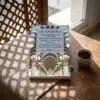 Libro 20 - Los modales y el carácter ético del Profeta de Imam Al-Gazzali, sobre una mesa de madera con la sombra de una celosía