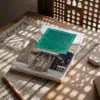 Libro 3 - Los misterios de la purificación y de sus aspectos esenciales de Imam Al-Gazzali, sobre una mesa de madera con la sombra de una celosía