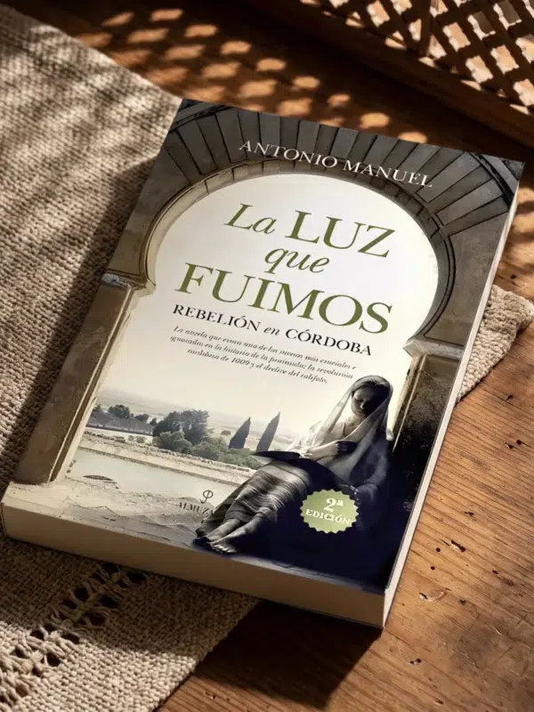 La luz que fuimos de Antonio Manuel, sobre una mesa de madera con la sombra de una celosía